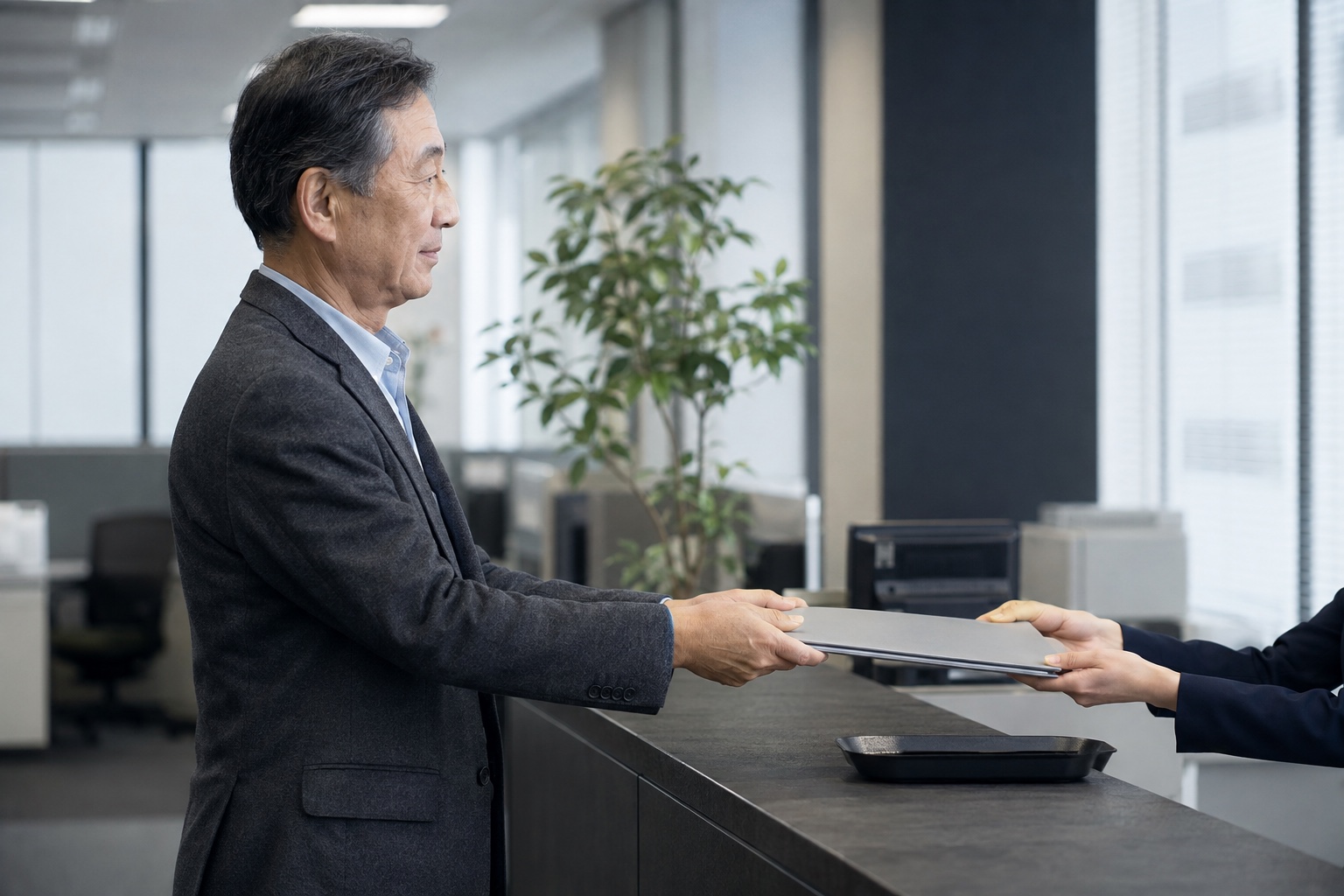 職場の人事窓口で退職手続のフォルダーを提出する会社員